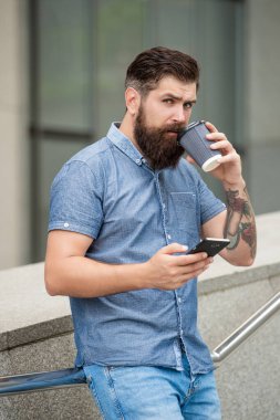 Sakallı adam dışarıda kahve içerken cep telefonuyla mesaj atıyor. Akıllı telefondaki mobil uygulama kullanılarak mesaj gönderiliyor. Mobil iletişim. Mobil aygıtta çevrimiçi sohbet.