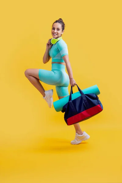 fitness woman in sportswear running with sport bag in studio. fitness woman in workout sportswear isolated on yellow background. fitness and sportswear.