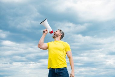 Sarı gömlekli adam arka planda megafonla bağırıyor. iletişim.