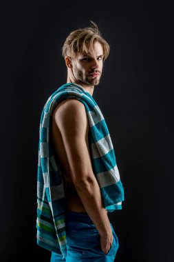 Stüdyo arka planında kaslı kaslı bir adam. Kaslı adam karın kaslarına havlu takıyor. Kaslı bir adamın fotoğrafı. Siyah arka planda izole edilmiş karın kaslarında havlusu olan kaslı adam..