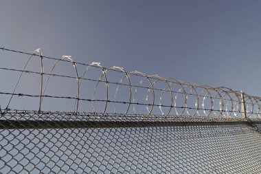 Keskin çelik dikenli dikenli telle sarmalanmış. Güvenlik ve güvenliği sağlıyorum. Dikenli tel. Hapishane duvarı. Dikenli tel örgülü yüksek korumalı hapishane duvarı. çelik parmaklık..