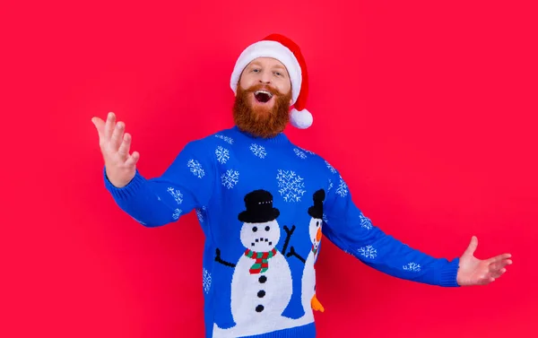 caucasian singing man in christmas sweater and santa hat isolated on red background. man celebrating christmas. merry christmas.