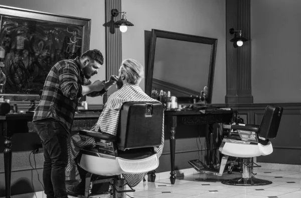 Touching his perfect beard. male beauty and fashion. mature man at barbershop. brutal bearded man at hairdresser. professional barber with male client. hipster with dyed beard and moustache.