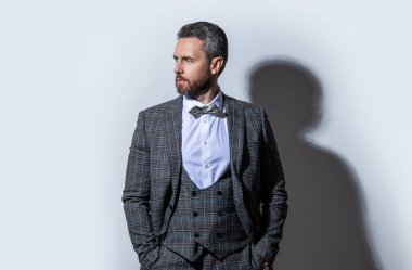 Stüdyodaki smokinli adam. Smokin giyen adamın fotoğrafı. Adam smokin resmi takım elbise giyiyor. Gri arka planda smokinli adam..