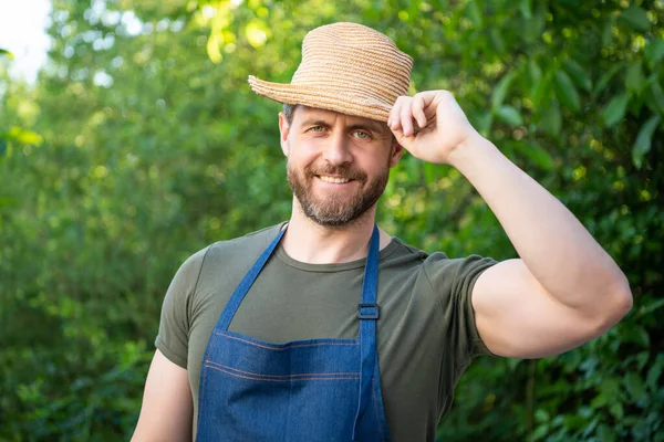 Happy farmer man tipping farmers hat and smiling natural outdoors.