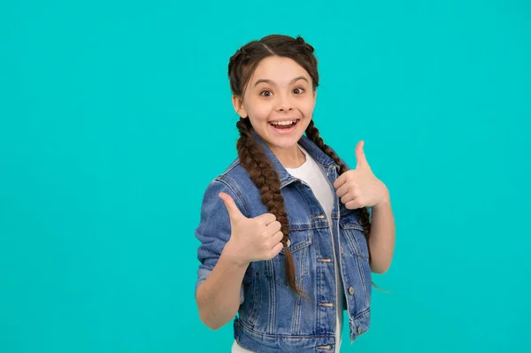 Beauty at its best. Happy child give thumbs up blue background. Little girl smile gesturing thumbs up. Hair salon. Haircare cosmetic products. Approval gesture. Hand sign. She deserves thumbs up.
