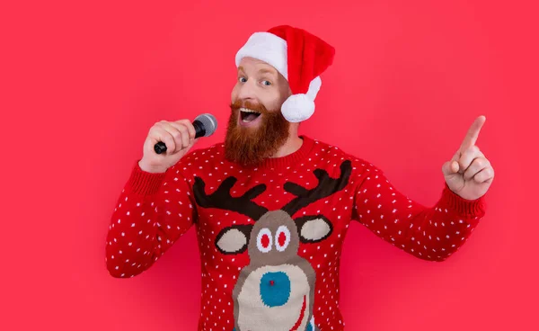 christmas karaoke music. man singing christmas music in karaoke and point finger. christmas santa man singing karaoke music isolated on red background.