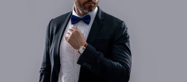 Stüdyodaki resmi smokinli adamın görüntüsü. Resmi smokin giyen bir adamın fotoğrafı. Erkekler resmi smokin giyer. Resmi smokinli adam gri arka planda izole edilmiş..