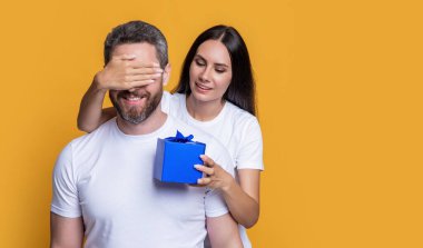 Sarı arka planda sürpriz hediyeli çift var. Sürpriz çift stüdyoda. Noel kutulu tatil çifti. Bayram sürprizi için hediyeli bir çift fotoğrafı. Erkekler Günü.