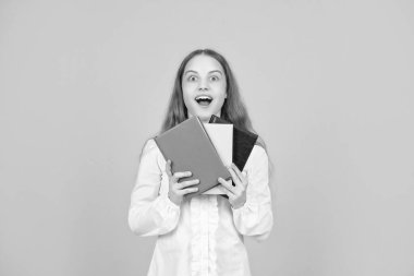 Şaşırmış çocuk sarı arka planda ders kitabı tutuyor, çalışıyor..