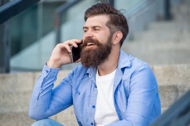 Kafkasyalı adamın dışarıda akıllı telefon görüşmesi var. Adamın dışarıda akıllı telefon görüşmesi var. Adamın sokakta akıllı telefonları var. Fotoğrafta akıllı telefon var..