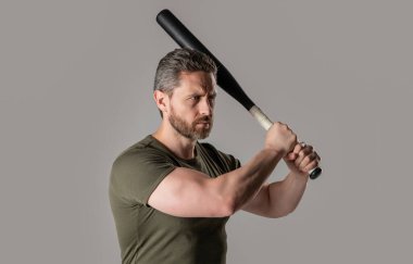 Kızgın adamın sopayla vurduğu fotoğraf. Kızgın adam tehdit ediyor. Öfkeli adam, gri arka planda izole edilmiş yarasayla öfkesini ifade eder. Stüdyoda sopalı kızgın adamın saldırganlığı..