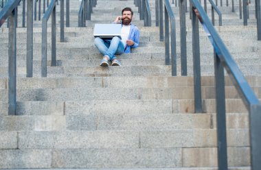 Adamın dizüstü bilgisayarında video bağlantısı var, kopyalama alanı. Adamın dışarıda online video iletişimi var. Adamın dışarıda çevrimiçi video bağlantısı var. Adamın merdivenlerde online video bağlantısı var..