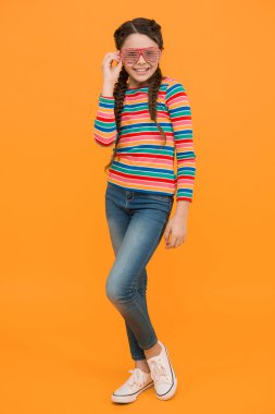 Saçları örgülü neşeli çocuk sarı arka planda renkli kıyafetler ve büyüleyici parti gözlükleri takıyor. Duyguları var..