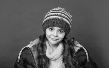 Kırmızı arka planda örgü şapkalı ve ceketli pozitif çocuk, genç..