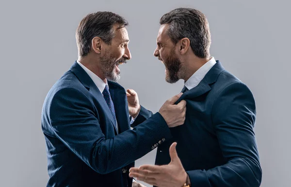 two arguing businessmen shout in conflict isolated on grey background. businessmen have conflict in studio. conflict of businessmen shouting. photo of businessmen conflict with anger.