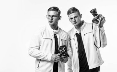 Erkek arkadaş. Retro fotoğraf makinesi olan iki kuzen. Kendine güvenen genç kardeşler. Kendine güvenen bir fotoğrafçı. Beyazlı ikiz kardeş. Fotoğrafçılık. Güzellik ve moda. Benzer görünüş. erkek arkadaşlığı.