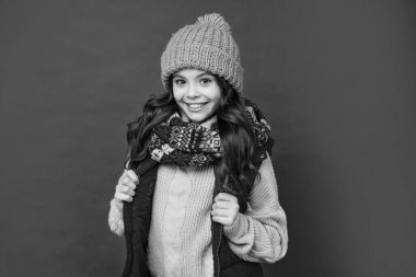 Kış şapkalı mutlu çocuk ve kırmızı arka planda eşarp, portre.