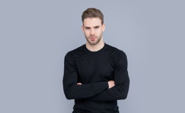 Gri arka planda sakallı, kendine güvenen bir adam var. Sakalı olan beyaz bir adamın yüzü. Tüylü ve sakallı. Stüdyoda sakallı bir adamın portresi..