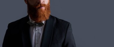 Stüdyo, smokin giysisinin manzarasını kesmiş. Smokin giyen adam. Smokin resmi kıyafet. Smokinli sakallı adam gri arka planda izole edilmiş..