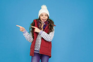 Orada xmas indirimi var. Yeni yıl tatiline hazırım. Hipotermi yok. Neşeli kız kıyafet katmanları giyer. Kış mevsiminde kalın giysiler. Soğuk hava tahmini. Çocuk moda alışverişi. işaret parmağı.