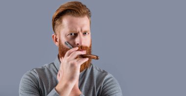 Adam tıraş olmak için berber bıçağını tutuyor. Gri stüdyo geçmişinde berber bıçağıyla tıraş olan bir adam. Berber adam bıçakla tıraş oluyor. Berber stüdyosundaki adam.