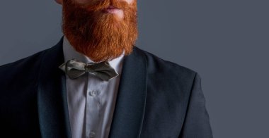 Smokin resmi kıyafet. Smokinli sakallı adam gri arka planda izole edilmiş. Smokin giysisiyle çekilen bir erkek stüdyosu. Smokin giyen sakallı adam..