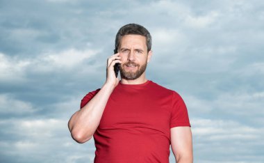 Adamın gökyüzü geçmişinde telefon konuşmaları var. Adam dışarıda telefonla konuşuyor. Adam telefonda konuşuyor, kırmızı tişört giyiyor. Bir adamın fotoğrafı telefonda konuşuluyor..