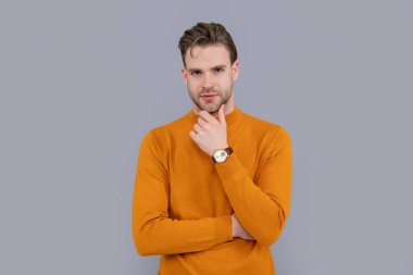 Gri yolda izole edilmiş bir adam. Yakışıklı, gri bir altyapısı var. Çenesini çarpan ciddi bir adam. Gündelik giysili beyaz bir genç..