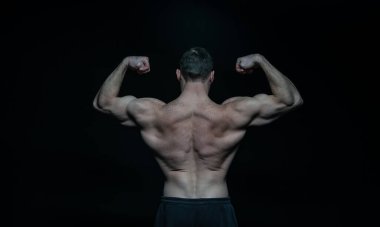 Siyah stüdyoda vücut geliştiren kaslı adam. Vücut geliştiren kaslı adam arka planda. Vücut geliştiren kaslı adamın fotoğrafı. Vücut geliştirici, kaslı, siyah sırtlı..
