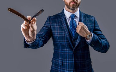 Traş bıçağıyla berber, seçici odaklanma. Berber stüdyosunda bıçaklı bir adam. Berber bıçaklı sakallı adamın fotoğrafı. Berber adam, gri arka planda bıçak tutuyor..