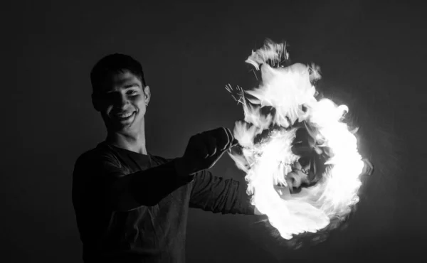 Happy guy artist perform fire circle by spinning burning poi on idyllic dark sky at night outdoors, orbital.