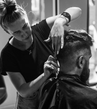 Beş dakika içinde hazır olacağım. Profesyonel berber ustası olan adam elektrikli tıraş makinesi kullanıyor. Erkek berber bakımı. Kuaför salonundaki sakallı adam. Güzellik ve moda. saç ve sakal şekillendirme.