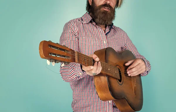 brutal caucasian hipster with beard in shirt play acoustic guitar, song writer.