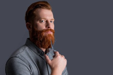 Berber makasıyla kuaförlük, fotokopi alanı. Kuaför stüdyosunda berber. Berber adam kuaförlük için makas tutuyor. Kuaförlük konsepti. Berber kuaförlüğü gri renkte izole edilmiş..