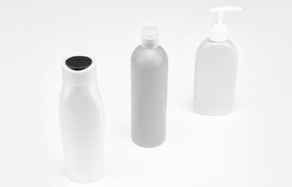 Multicolor plastic refillable liquid toiletry product containers in row isolated on white copy space, bottles.