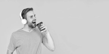 Tüylü şarkı söyleyen adam müzik dinliyor sarı arka planda kahve içiyor, müzik çalıyor..