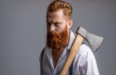 Baltalı, sakallı, erkeksi bir adamın fotoğrafı. Baltası gri renkte olan erkeksi bir adam. Stüdyoda baltası olan erkeksi bir adam. Arka planda balta olan erkeksi bir adam..