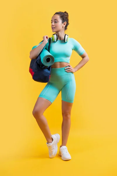 fitness woman in sportswear with sport bag in studio. fitness woman in sportswear isolated on yellow background. fitness and sportswear.