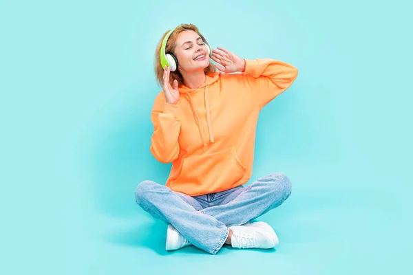 cheerful cool woman listen music isolated on blue background. cool woman listen music at studio. photo of cool woman listen music in headphones. redhead cool woman listen music on color background.
