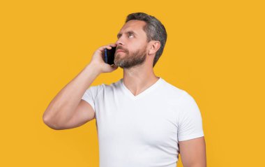 Düşünen adam iletişim akıllı telefonunda konuşur. Adam akıllı telefon konuşmaları yapıyor. İletişim konsepti. Akıllı telefondan konuşan adam sarıda izole edilmiş. Stüdyoda adam akıllı telefonda konuşur..