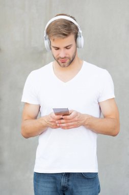 Yakışıklı adam mp3 müzik listesini beyaz gömlekle seçiyor. İnsan mp3 müzik listesinin kulaklıkla fotoğrafı. Adam mp3 müzik listesini açıyor. Adam dışarıda mp3 müzik listesi kullanıyor.