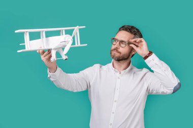Hırslı bir adam uçakla isteklerini başlatır. İnsanoğlunun oyuncak uçakla heveslerini fırlatma fotoğrafı. Mavi arka planda izole edilmiş erkek fırlatma özlemleri. Stüdyoda adam başlatma arzusu.