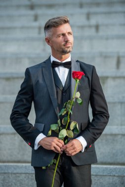 Aşk randevu konsepti. Aşk güllü beyaz smokinli adam. Aşk günü için çiçek hediyesi..