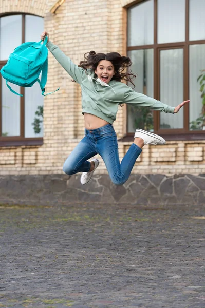 school girl childhood jump outdoor. school girl jump childhood outside. school girl jump childhood at the street. photo of school girl jump childhood with backpack.