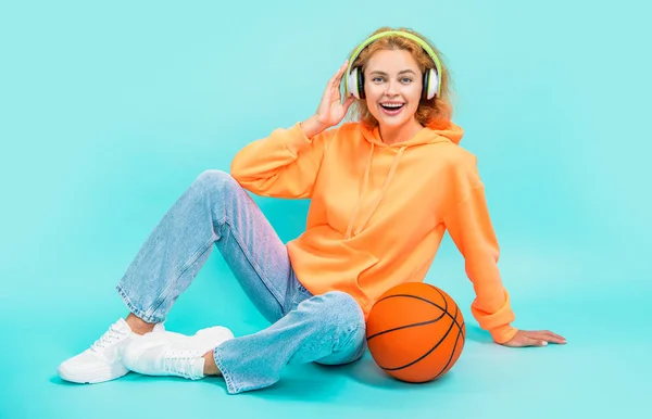 happy basketball woman player isolated on blue background. basketball woman player at studio. photo of basketball woman player in hoodie. redhead basketball woman player on color background.