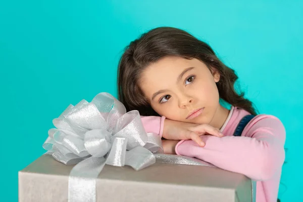 dreamy girl with birthday gift on background. photo of girl with birthday gift box. girl with birthday gift isolated on blue. girl with birthday gift in studio.