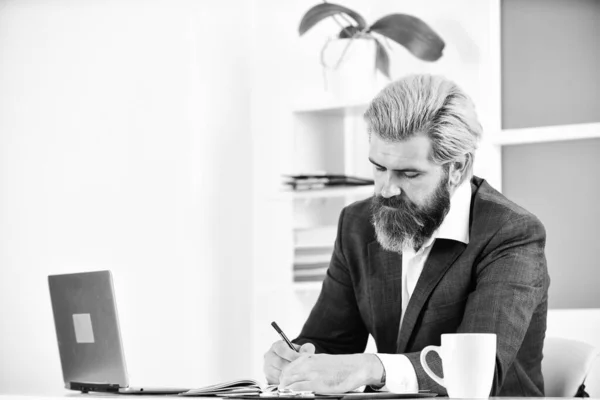 Full concentration at work. Elegant businessman analyzing data in smartphone. Quarantine agile business. lawyer use notebook for work. bearded man sit at desk in office. confident brutal businessman.