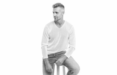 Gülümseyen, beyaz saçlı, olgun, yakışıklı bir adam beyaz arka planda izole edilmiş bir sandalyeye oturuyor..