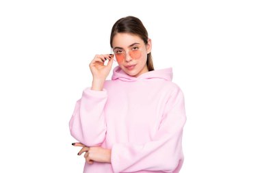 Serious girl in casual pink hoodie adjusting glasses isolated on white, fashion.